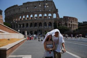 Itália – Turistas se protegem do sol e do intenso calor em Roma, na Itália, enquanto caminham em frente ao antigo Coliseu de Roma, um dos pontos turísticos mais famosos do mundo. Foto: Alessandra Tarantino/AP Photo.