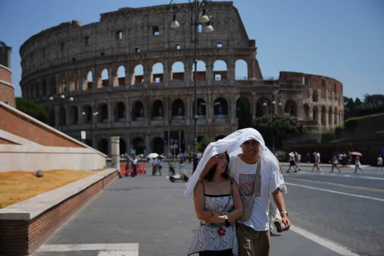 Itália – Turistas se protegem do sol e do intenso calor em Roma, na Itália, enquanto caminham em frente ao antigo Coliseu de Roma, um dos pontos turísticos mais famosos do mundo. Foto: Alessandra Tarantino/AP Photo.
